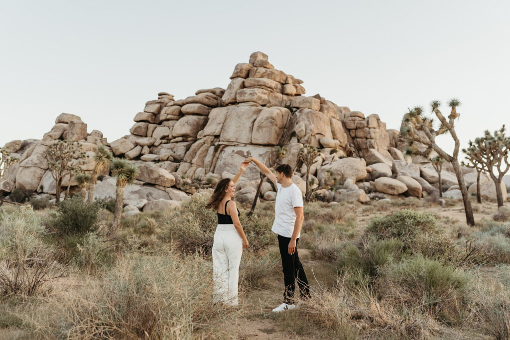 a female and male couple taking photos in Joshua Tree during their engagement session. 
